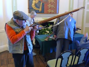 A museum visitor handles a Brown Bess musket at a weapons demonstration.