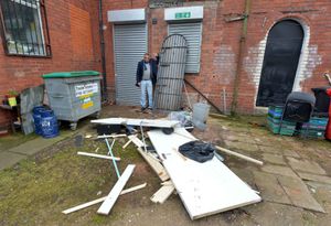Basharat Khan surveys the damage caused in the raid as he stands in front of the new steel shutter he has installed