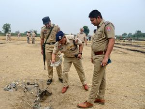 Indian police personnel inspect an object suspected to be parts of a projectile intercepted by the Indian Army at Nahlan village