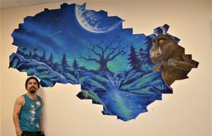 Mural artist Rory McCann with the Gruffalo mural he hand painted in the pre-operative area