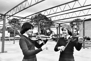 The caption reads: 'Trying out a few bars beneath the girdered framework of the octagonal music room being built at Ludlow School are 14-year-olds Angela Morley and Sarah Cheadle. The room is due to be completed by September 1978.' 