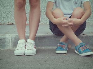 Close-up of two teenagers sitting and standing in the street