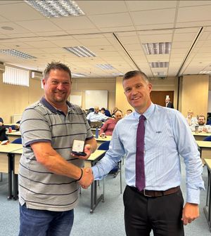 Ash Forster being given a commemorative coin by West Midlands Police Federation's Rich Cooke before retiring