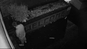 A man stands against the wall with its 'Welcome' sign