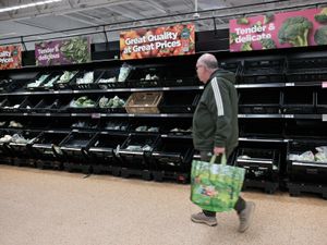 A man walks past the vegetables section of an Asda supermarket