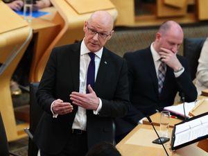 John Swinney standing while speaking in Parliament