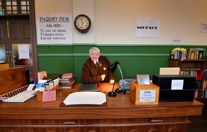 Leonard Hughes sits behind the desk of the library