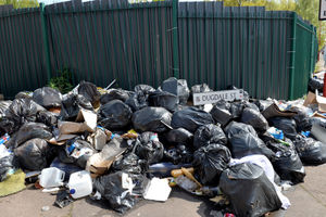 Bags of household waste from the edge of the path to the fence