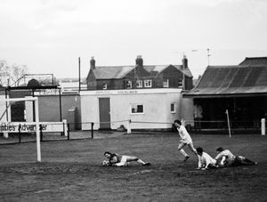 Football match between Oswestry Town FC and Buxton played on Saturday, February 4, 1984, at Oswestry Town ground at Victoria Road. The result was a 3-3 draw. The photographer's caption was 'The Buxton defence in total disarray with the keeper using his fingernails to save a goal.'