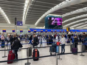 Passengers queue to check-in bags in departures at Terminal 5 of Heathrow Airport