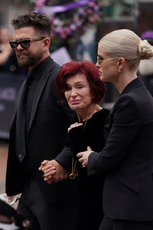 The family of Ozzy Osbourne (left to right) Jack, Sharon and Kelly Osbourne, view the messages and floral tributes left at the Black Sabbath Bridge bench on Broad Street in Birmingham in memory of Black Sabbath frontman Ozzy Osbourne, as his body is brought back to his home city for a procession following his death last week aged 76. Picture date: Wednesday July 30, 2025. PA Photo. Photo credit should read: Joe Giddens/PA Wire