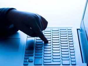 The hand of a young child using a laptop