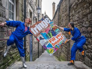 Two performers hold a sign that reads 'fringe - fill yer boots'