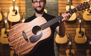 guitarguitar's Robbie Tranter with the guitar signed by Noel Gallagher
