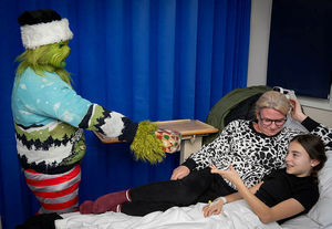 The Grinch with mum Jill Moffatt and daughter Beau Melligan receiving her present on the bed
