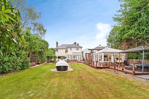 The landscaped rear garden features a decked hot tub area