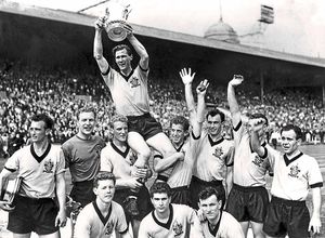 Malcolm, second left, celebrates as captain Bill Slater lifts the FA Cup
