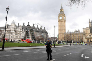 An armed policeman stands in a deserted street in front of the Houses of Parliament
