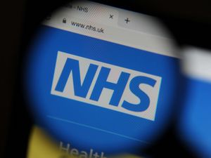 The NHS website seen through a magnifying glass on a computer