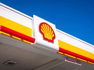 The Shell logo on the top of a petrol station, under blue skies