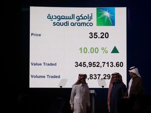 Saudi Arabia’s state-owned oil company Armco and stock market officials walk under a screen displaying the value traded and the volume traded of Aramco’s initial public offering (IPO) on the Riyadh’s stock market in Riyadh, Saudi Arabia