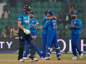 Jos Buttler, left, walks off the field as Afghanistan players celebrate