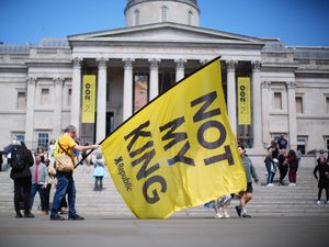 A large yellow flag bearing the words 'not my king' is waved during an anti-monarchy rally in Trafalgar Square