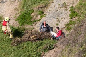 A rescue worker reaches Mark Weaver, from Telford, the girl and Tony Roberts, from Shrewsbury, on the cliff at the seaside resort in Wales