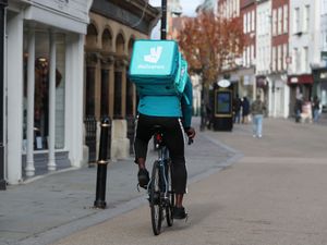 A Deliveroo rider cycling on a high street