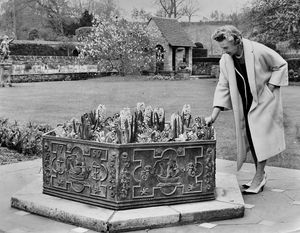'Mrs M.H. Rollason pictured in the grounds of her historic home.' This is a picture from the Express and Star picture archive with the Express & Star stamp. Date stamp on the print is May 1, 1962. It also has the written date April 30, 1962, which may well be when the photo was taken. The story pasted on the back of the print reads: 'If your 'garden' at home happens to be a window box, or if you have a garden and you want a rest from gardening, there's nothing nicer than a visit to someone else's gardens. This Sunday it could be a visit to lovely, historic Ludstone Hall at Claverley. Because that is the day that Mr and Mrs M.H. Rollason are allowing the grounds of the hall to be open to the public. All in aid of a cause in which Mrs Rollason is particularly interested... (n.b. cut off here, so we don't learn what the cause is).\ The photographer looks like Nickhelas or something else beginning with Nick. Library code: Claverley nostalgia 2012.
