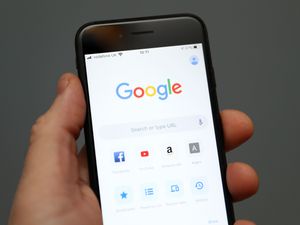 A person holds an iphone showing the app for Google chrome search engine