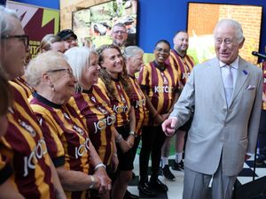 Charles laughing as he talks to some choir members who are wearing Bradford City shirts