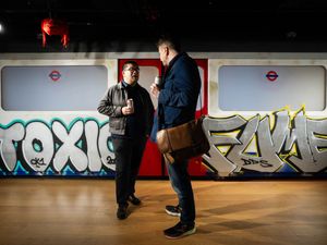 Two men in front of an Underground train covered in grafitti