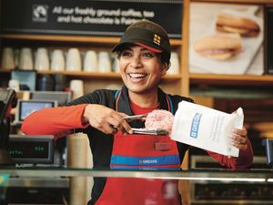 A Greggs worker serving a doughnut