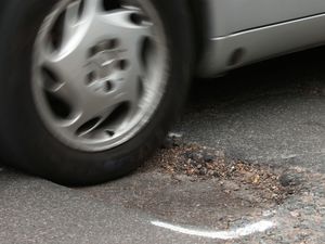 A car hits a pothole on a road i