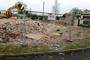 Bulldozers flatten the former pub at Four Crosses on the side of the A41 to make way for new homes