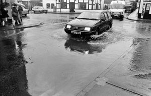 nostalgia pic. Oswestry. This is a print from the Shropshire Star picture archive and the photographer's date on the back is 16.1.84, i.e. January 16, 1984, which will be when it was taken. The caption pasted on the back reads: 'Problems for motorists and pedestrians as thousands of gallons of rain water flooded down Brook Street.' The print also has the date 17/1/84, i.e. January 17, 1984, which was publication date. The story said several roads in the Welsh Walls area of Oswestry were flooded by a torrent of water when a stream became blocked. The source of the problem was a stream at the top of Brynhafod Lane which was blocked by fallen leaves and overflowed its banks into the street. The print has the Shropshire Star copyright stamp and the photographer was Mac Ozanne. Oswestry flood. Oswestry flooding. Oswestry floods. Library code: Oswestry nostalgia 2015.
