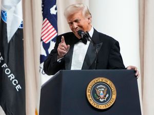 Donald Trump speaks on stage from behind a podium at the Commander in Chief Ball