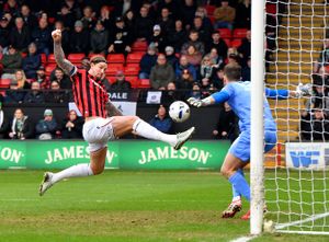 Walsall defender Aden Flint stretches to meet Evan Weir's free-kick delivery.