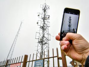 A man taking a photo of a mobile phone mast using a mobile phone