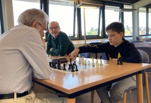11-year-old Finlay makes his move watched by the more experienced players.