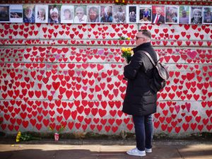 A man holding flowers at the Covid-19 memorial wall in London