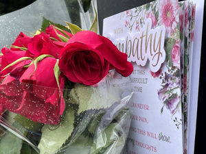 Flowers and a card left on signage outside the remains of The Crooked House pub near Dudley