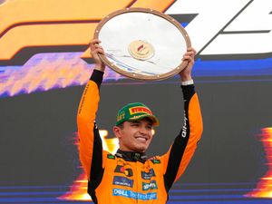 Lando Norris holds up the victory shield after winning