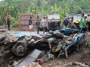 Police and people inspect the wreckage of a minibus after it collided with a dumper truck in Central Java Province in Indonesia