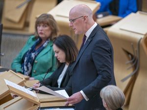 John Swinney standing while speaking in Parliament