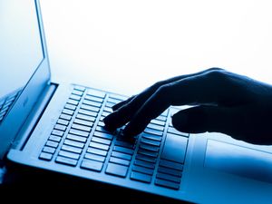 A woman's hand pressing the keys of a laptop