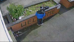 A man stands against the wall with its 'Welcome' sign
