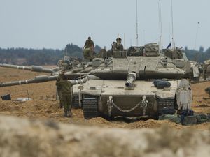 Israeli soldiers work on tanks and APCs at a staging area near the border with the Gaza Strip, in southern Israel