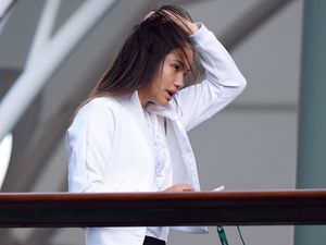 Emma Raducanu sweeps her hair back while on a balcony at Wimbledon last year